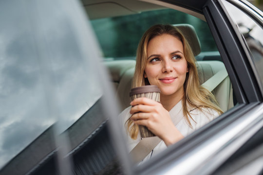 Business Woman With Coffee Sitting On Back Seats In Taxi Car.