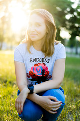 Portrait of a beautiful young modern woman with brown hair smiling and having fun outdoor in the summer, park with warm backlight at sunset