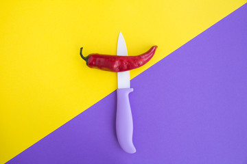 Pepper chile and violet knife on the two-color background. Top view. Copy space.