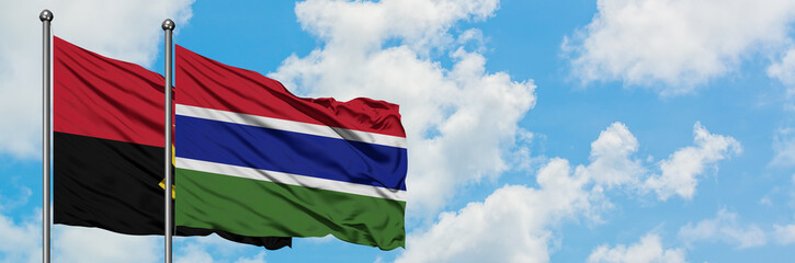 Angola and Gambia flag waving in the wind against white cloudy blue sky together. Diplomacy concept, international relations.