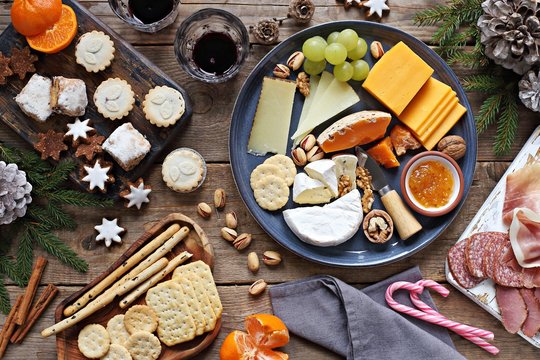 Festive winter appetizers table with various of cheese, curred meat, sweets, nuts and fruits. Festive family or party snack concept. Overhead view.