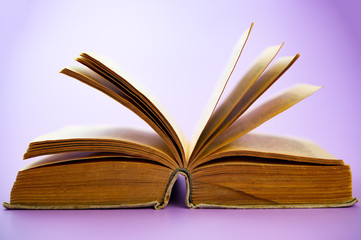 pages and an open old book on a lilac background.