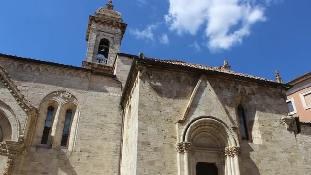 Right-Left pan view of the Church of San Quirico D'Orcia and the Chigi Zondadari palace with the Tuscany spring's blue sky. Holidays in the beautiful country immersed in art and culture. HD Video