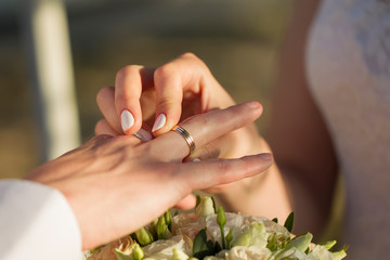 Obraz na płótnie Canvas Hands of the bride put a ring to the groom. Wedding day.