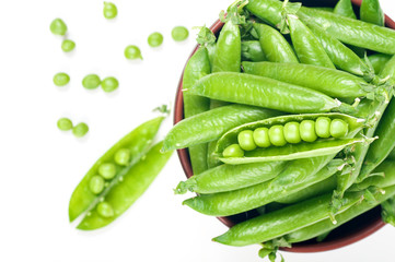 green peas in pods.  in a clay plate view from above on a white background