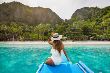 Back view of the young girl relaxing on the boat and looking at the island. Traveling tour in Asia: El Nido, Palawan, Philippines.
