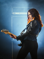 Beautiful woman with red hair playing electric guitar