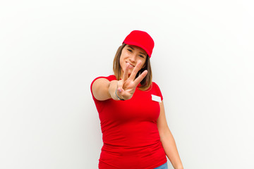 delivery woman smiling and looking friendly, showing number three or third with hand forward,...
