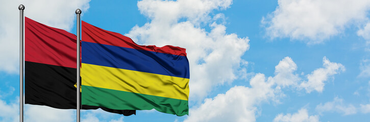 Angola and Mauritius flag waving in the wind against white cloudy blue sky together. Diplomacy concept, international relations.