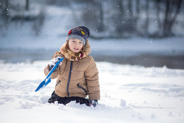 Boy having fun, playing outside, surrounded with snow. Wintertime.