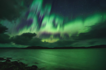 Northern Lights, Aurora Borealis in Kola Peninsula at night sky illuminated green. Murmansk region,...
