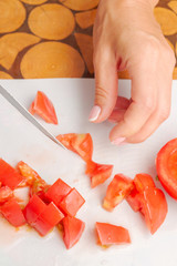 Dicing fresh ripe tomatoes on a white cutting Board