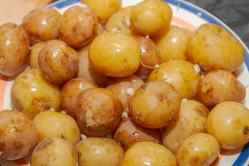Young boiled potatoes in uniform with garlic and butter lying on a plate
