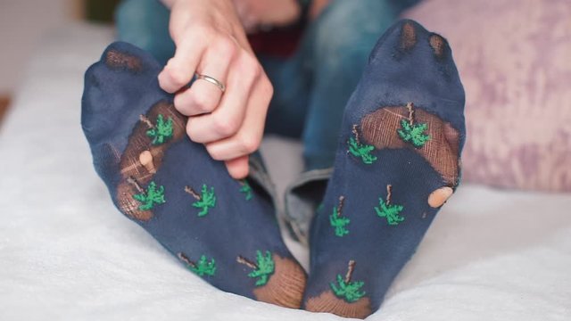 Man scratches his foot with his hand