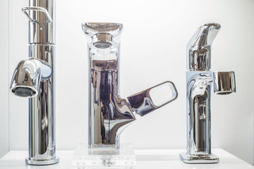 a variety of faucets taps on a white shelf in the store counter