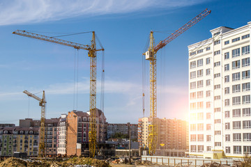 Fototapeta premium Construction site background. Hoisting cranes and new multi-storey buildings. I.ndustrial background.Building construction site work against blue sky