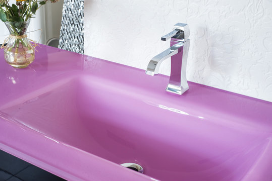 Close-up Of A Pink Stone Glossy Washbasin, In A Fashionable Interior, With Flowers. View From Above