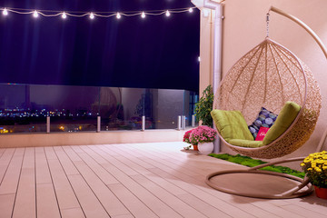 rooftop patio area with hanging swing chair and string lights at night