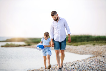 Mature father and small daughter on a holiday walking by the lake.