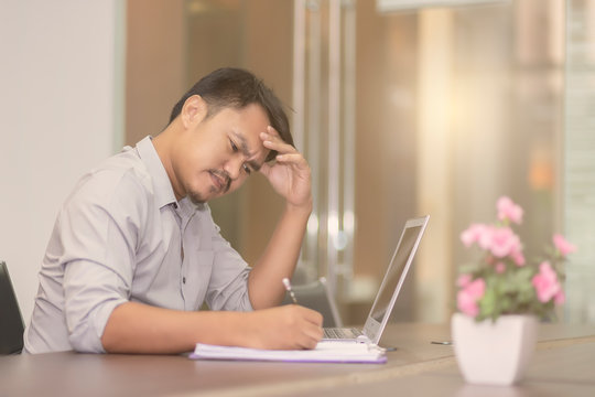 Asian business people are feeling stressed about the job with laptop and paper on the wooden table in the office. Asian men are worried when their work is unsuccessful.