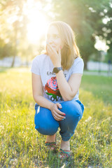 Portrait of a beautiful young modern woman with brown hair smiling and having fun outdoor in the summer, park with warm backlight at sunset