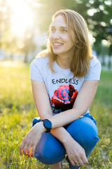 Portrait of a beautiful young modern woman with brown hair smiling and having fun outdoor in the summer, park with warm backlight at sunset