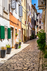Fototapeta na wymiar Narrow street with colourful building facades in romantic Town of Rovinj, Istra, Croatia