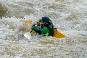 Man in a yellow kayak white water rafting