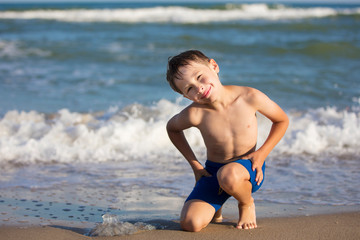 A boy on the beach is playing with a jellyfish. Child resting on the beach