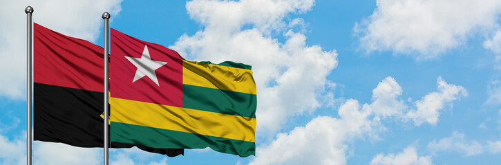 Angola and Togo flag waving in the wind against white cloudy blue sky together. Diplomacy concept, international relations.