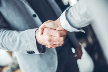 Male startupers working together at office standing handshake close-up