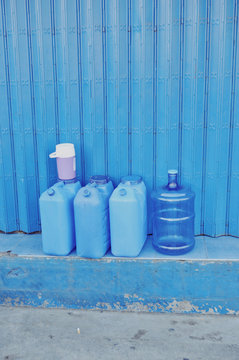 Direct view of gasoline cans and water placed next to blue wall