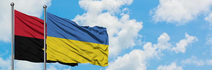 Angola and Ukraine flag waving in the wind against white cloudy blue sky together. Diplomacy concept, international relations.