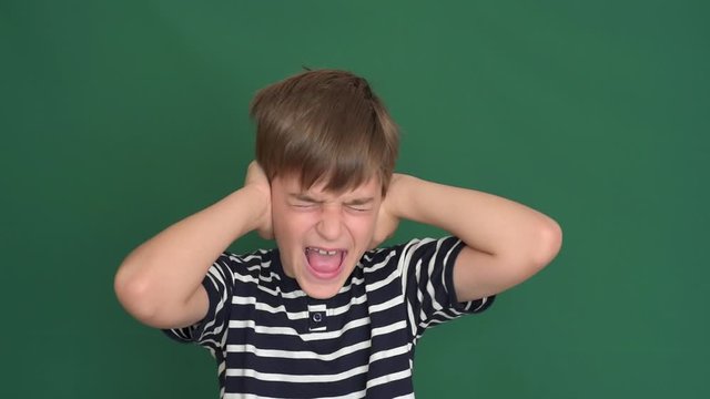 Young boy covering his ears with hands on the green screen