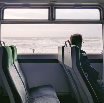 Man traveling in train looking at sea, Devon UK