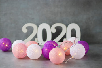 Christmas lights and white numbers 2020 on the gray background. Christmas and New Year concept.