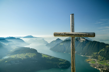 Wooden cross on viewing platform on top of Fronalpstock peak above the small village of Stoos
