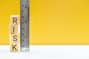 Risk assessment / risk analysis and management concept : Words RISK on wood blocks and a vertical ruler with scales, depict evaluation for financial risk of an investor involved in stock, bond market