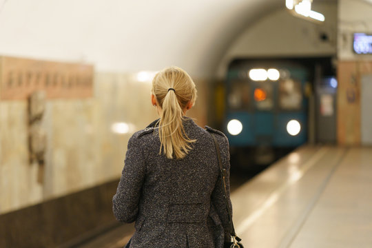 Photography of a woman waiting for the train car in Moscow subway. Image with train as defocused background.