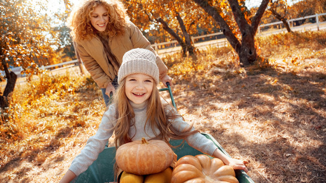 Young adult mother and daughter looking at carved pumpkin with smoke