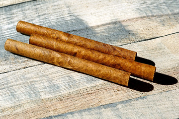 Three cigars on a wooden board