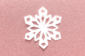 Large white paper snowflake on pink glitter backgound