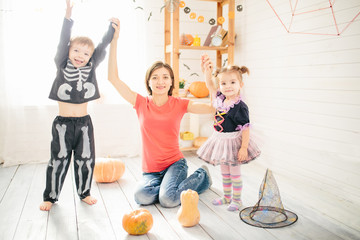 Fototapeta na wymiar Happy family of mother and children prepare for Halloween in decorate the home