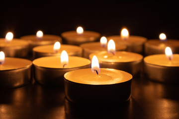Paraffin candles on a dark table, close-up. Symbol of memory.
