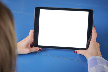 Mockup image: over shoulder view of woman looking at modern digital tablet computer device with white blank screen on blue table. Mock up, copyspace, leisure time, template and technology concept