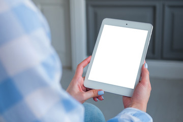 Mockup image: over shoulder close up view of woman looking at modern digital tablet computer device with white blank screen. Mock up, copyspace, leisure time, template and technology concept