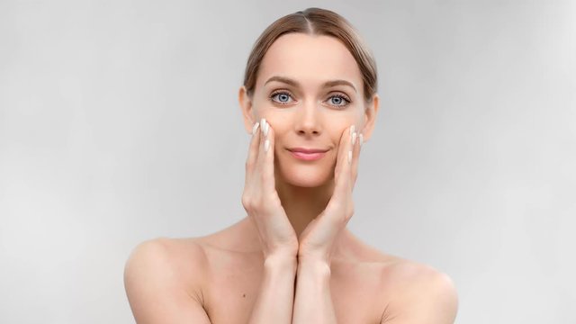 Portrait of naked woman applying moisturizing cosmetology cream isolated at white background