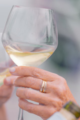 Photo detail of two hands together holding two glasses of white wine. Concept of celebration.