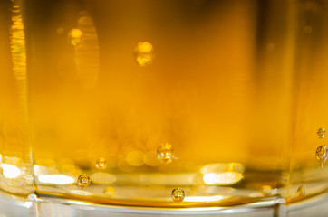 Close up of yellow sparkling drink with bubbles in glass 
