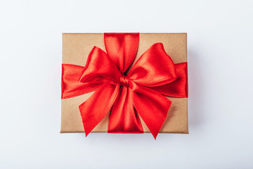 Cardboard gift box with red bow on white background.